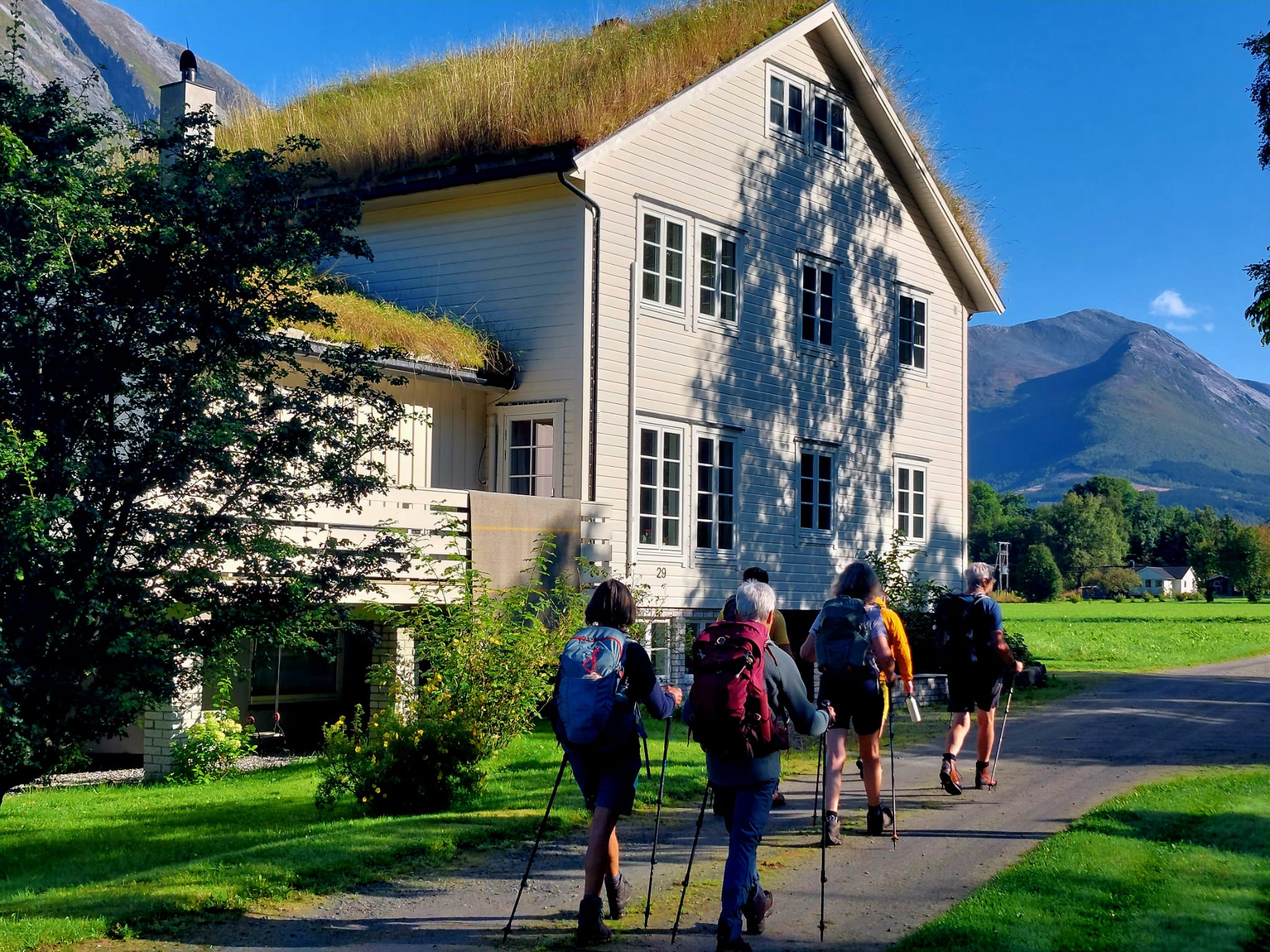 wandelaars in Noorwegen passeren langs wit houten huis