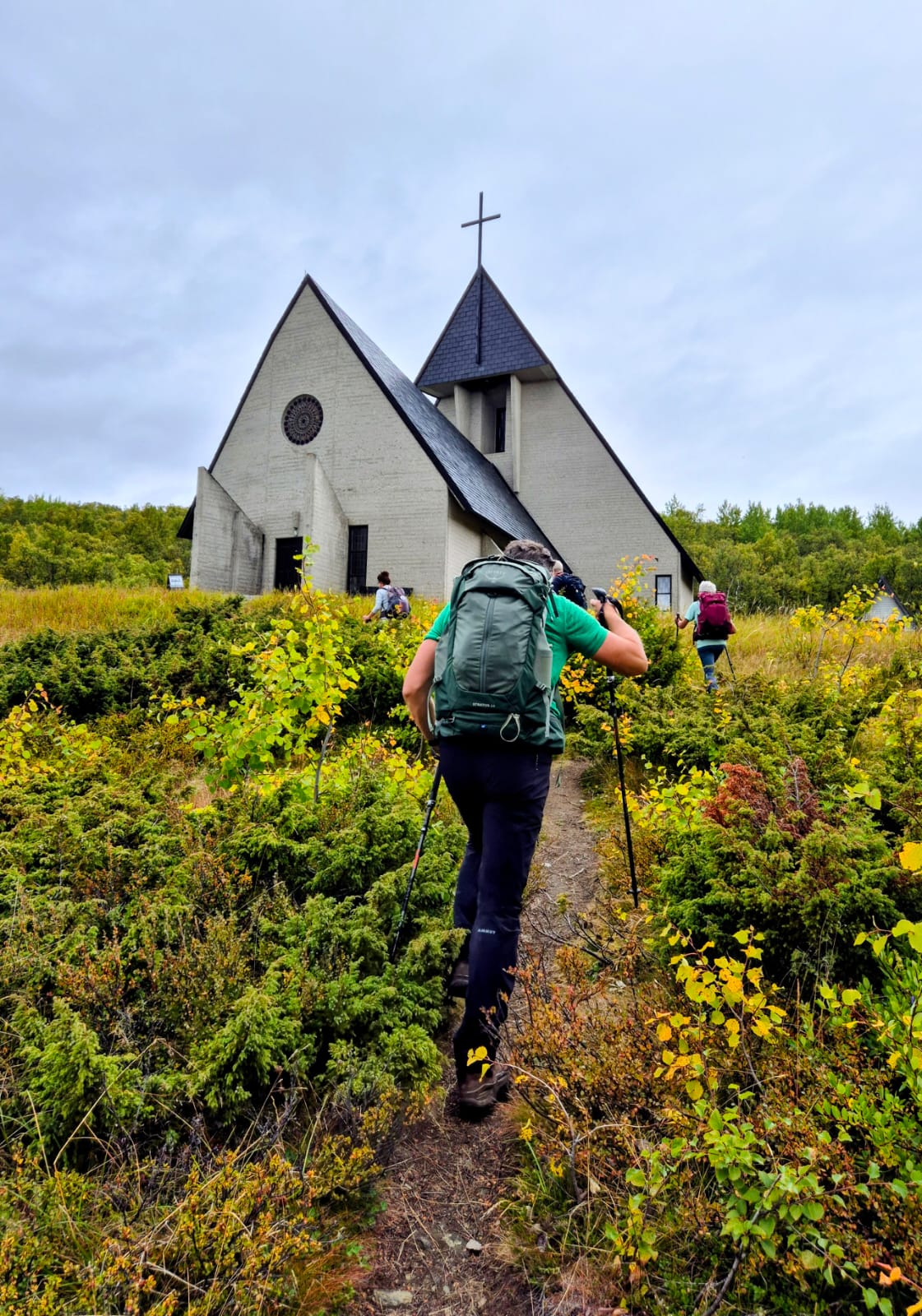 wandelaars in noorse toendra op weg naar witte kerk