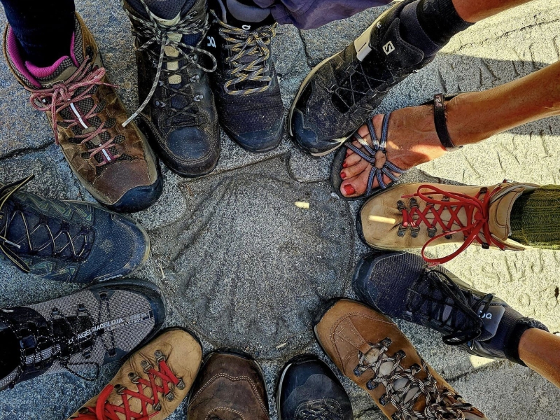 voeten met wandelschoenen rond een Sint Jacobsschelp motief in Santiago de Compostela