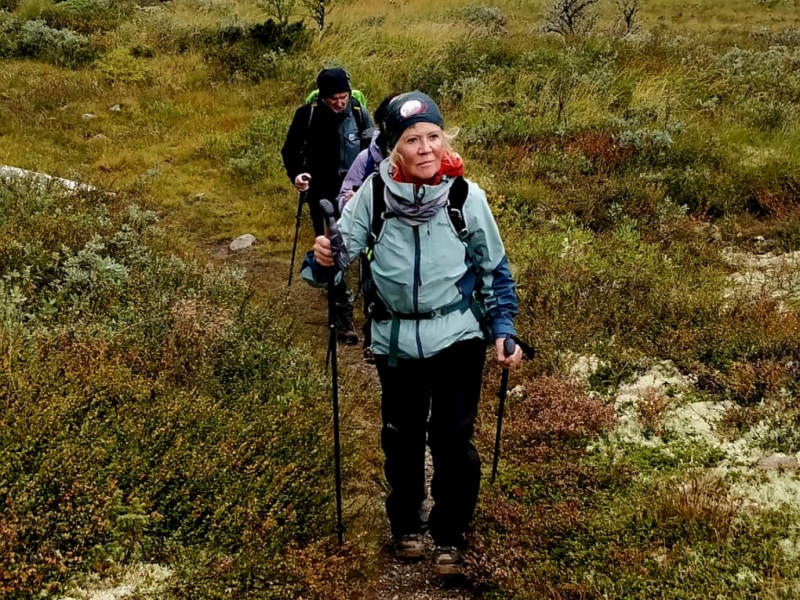 wandelaarster met wandelstokken in lage groene begroeing op het olavspad in noorwegen