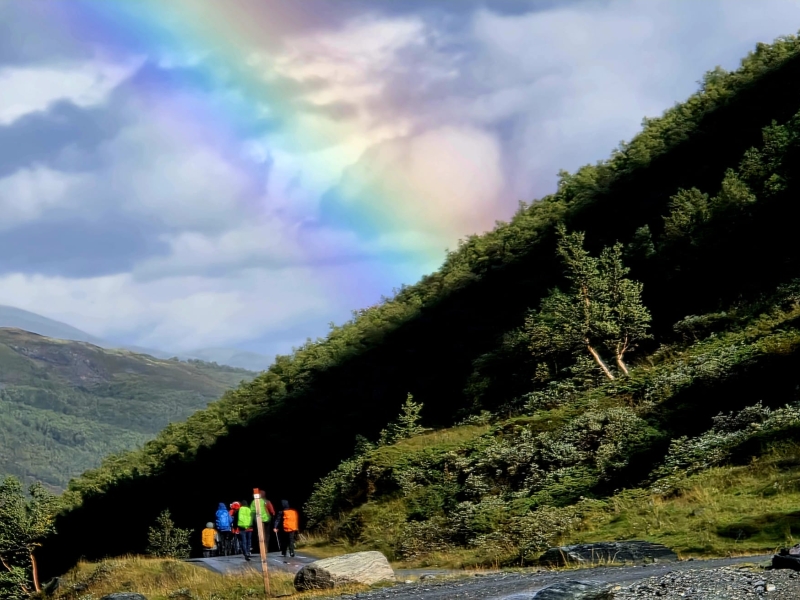 wandelaars in noorwegen met regenboog en bergen in de achtergrond
